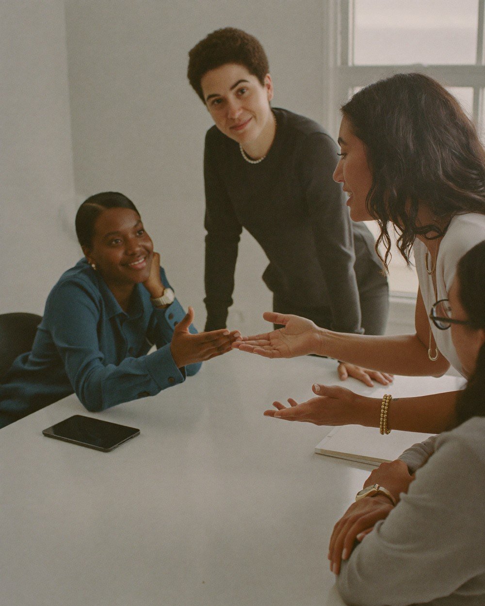 Quatro profissionais de uma PME em conversa de trabalho ao redor de uma mesa, gesticulando enquanto discutem