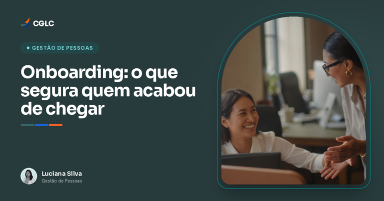 Colega experiente cumprimenta uma pessoa recem-chegada na mesa ao lado, em um escritorio pequeno