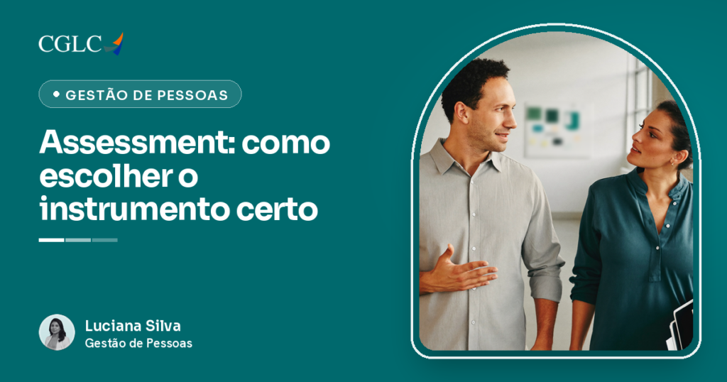 Homem de camisa cinza-clara e mulher de blusa verde-petróleo caminhando lado a lado por um corredor de escritório claro, virados um para o outro em conversa. Ele fala com a mão aberta na altura da cintura e ela escuta olhando para ele, com pastas fechadas sob o braço. Ao fundo, parede lisa, janelas altas e um quadro desfocado. Ninguém olha para a câmera e ninguém aponta o dedo.