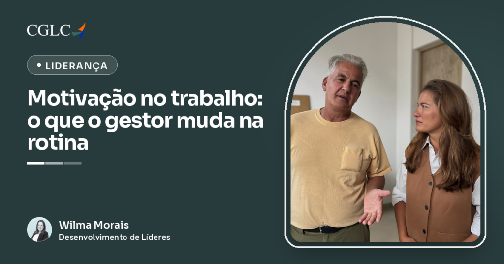 Homem grisalho de camiseta amarela conversando em pé com uma mulher de colete caramelo, os dois virados um para o outro diante de uma parede clara. Ele fala com a palma da mão direita aberta e voltada para cima; ela olha para ele.