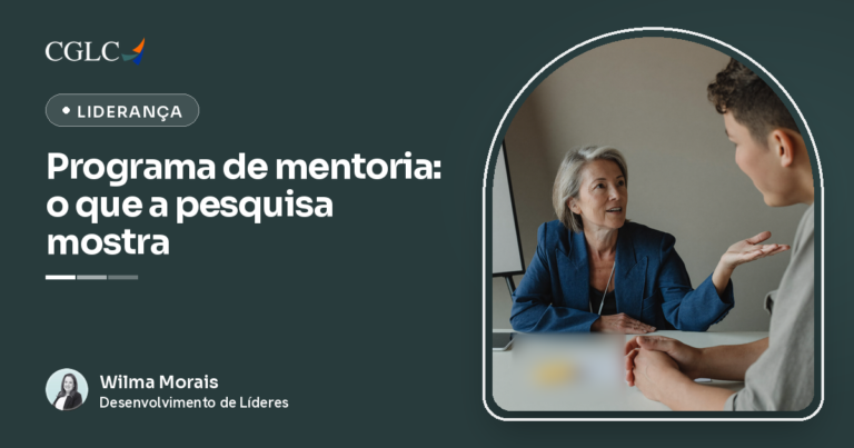 Capa do artigo, com fundo escuro de Liderança, a marca CGLC, o selo Liderança e o título Programa de mentoria: o que a pesquisa mostra. À direita, dentro de um arco, uma mulher de cabelo grisalho e blazer azul-marinho, sentada a uma mesa clara, gesticula com a mão aberta enquanto explica algo a um jovem de camiseta cinza, que ouve com as mãos entrelaçadas apoiadas na mesa. Ao fundo, um quadro branco vazio. No rodapé, a assinatura de Wilma Morais, da CGLC.